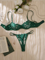 Frente Conjunto Penelope verde. Sutiã meia-taça bojo fino com aro, renda bordada floral e tule. Calcinha fio dental, renda e tule.