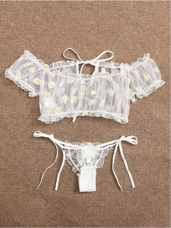 Conjunto Luiza frente, branco. Blusa cropped ciganinha e calcinha fio dental em renda transparente com margaridas, babados e laços.