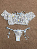 Conjunto Luiza azul, frente. Cropped ombro a ombro e calcinha fio dental de renda floral em tule com margaridas, babados e laços.