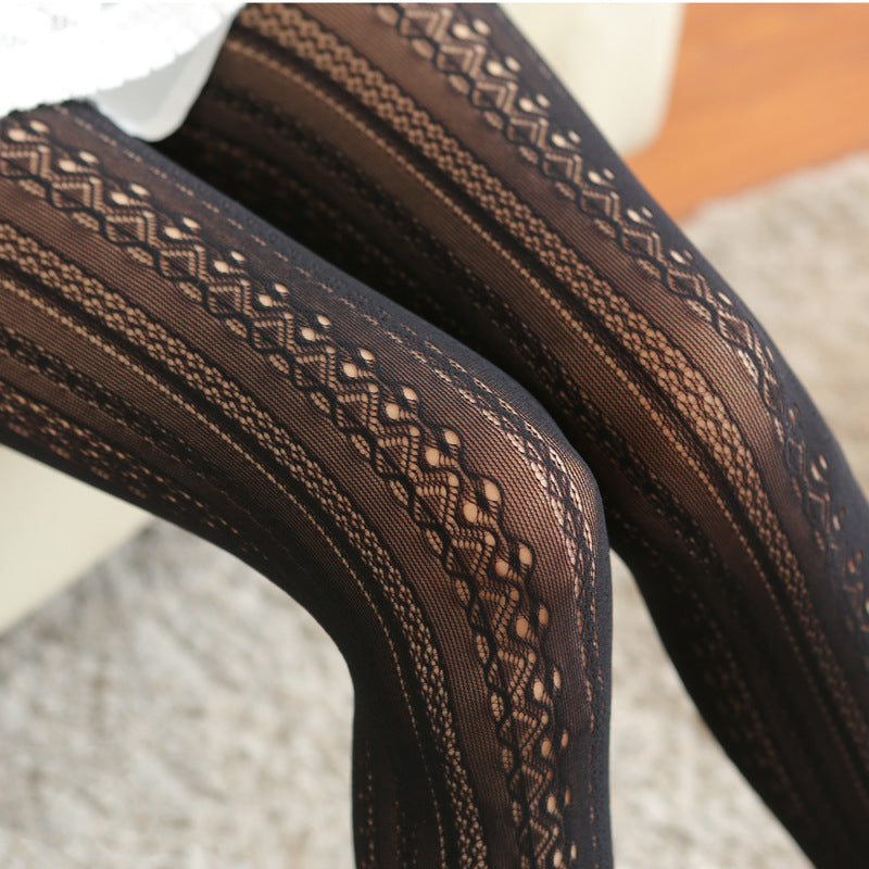 Meia-calça Lilia preta NuAuge, detalhe. Translúcida, com padrão de renda jacquard em listras verticais que alongam as pernas.