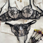 Conjunto Florinda Preto frente. Sutiã meia-taça com aro e bojo, tule transparente com bordado floral, calcinha fio dental.