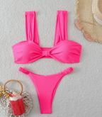 Biquíni Soleil rosa fluorescente. Top bandeau com bojo, laço central e alças largas. Calcinha cavada franzida.