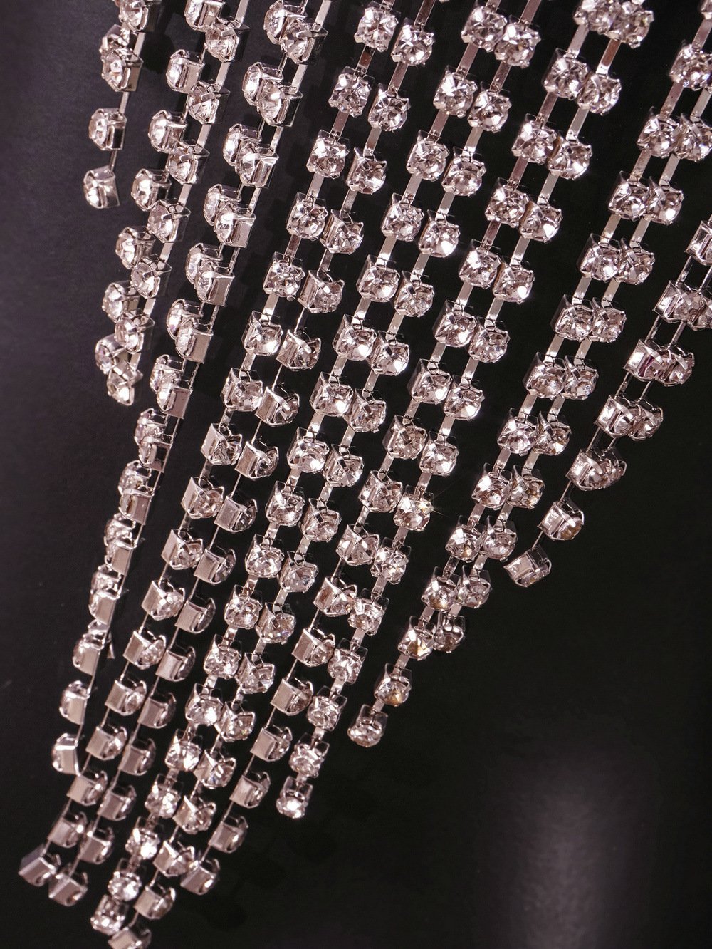 Detalhe Body Chain Supernova NuAuge, correntes prateadas com múltiplos cristais quadrados cintilantes.