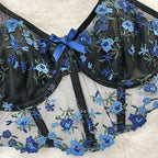 Detalhe frontal do sutiã Mirella preto e azul. Sutiã longline bicolor em malha fina com aro, bordado floral e laço.