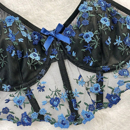 Detalhe frontal do sutiã Mirella preto e azul. Sutiã longline bicolor em malha fina com aro, bordado floral e laço.