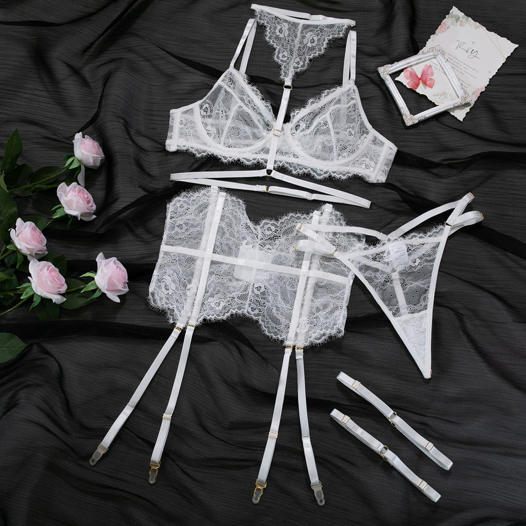 Conjunto Evangeline branco. Sutiã renda cílios c/aro, tiras; cinta-liga fishbone c/ligas; fio dental renda. Flat lay.