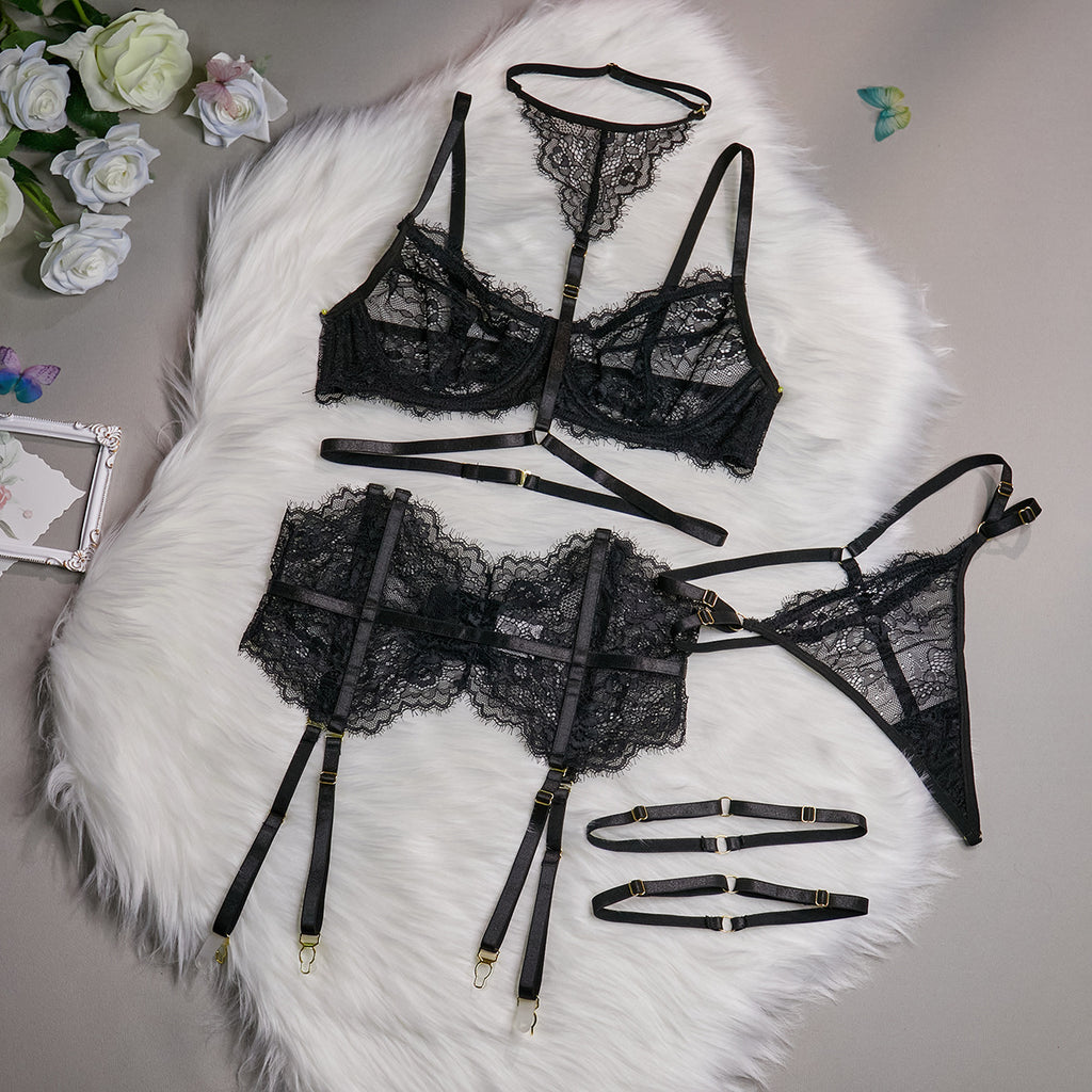Vista aérea do Conjunto Evangeline preto: sutiã de renda com aro, calcinha fio, cinta-liga fishbone, choker e ligas de coxa.
