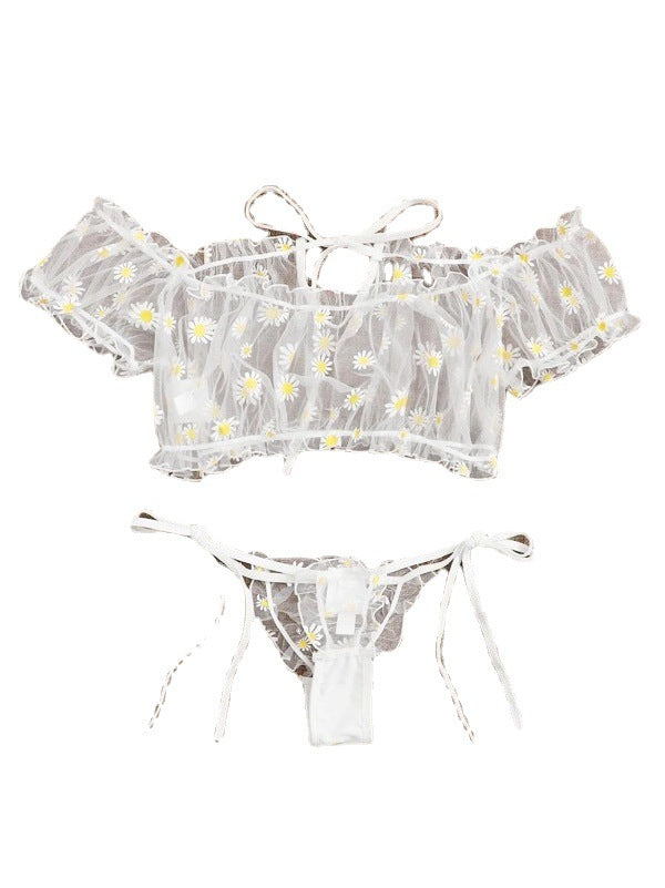 Foto de frente Conjunto Luiza branco. Top cropped ombro a ombro e calcinha fio dental com amarrações laterais, ambos em renda floral com margaridas, sem bojo e sem aro.