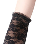 Detalhe Luva Valeria preta NuAuge. Renda floral fingerless com babado delicado na borda superior, toque retrô.