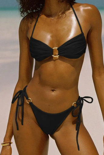 Biquíni Amalfi NuAuge preto - modelo na praia, vista frontal de corpo inteiro, top com argola dourada e calcinha de amarrar