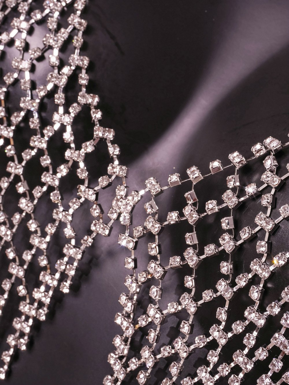 Detalhe do Body Chain Supernova prata NuAuge. Malha de strass reluzente, acessório de luxo para brilho celestial.