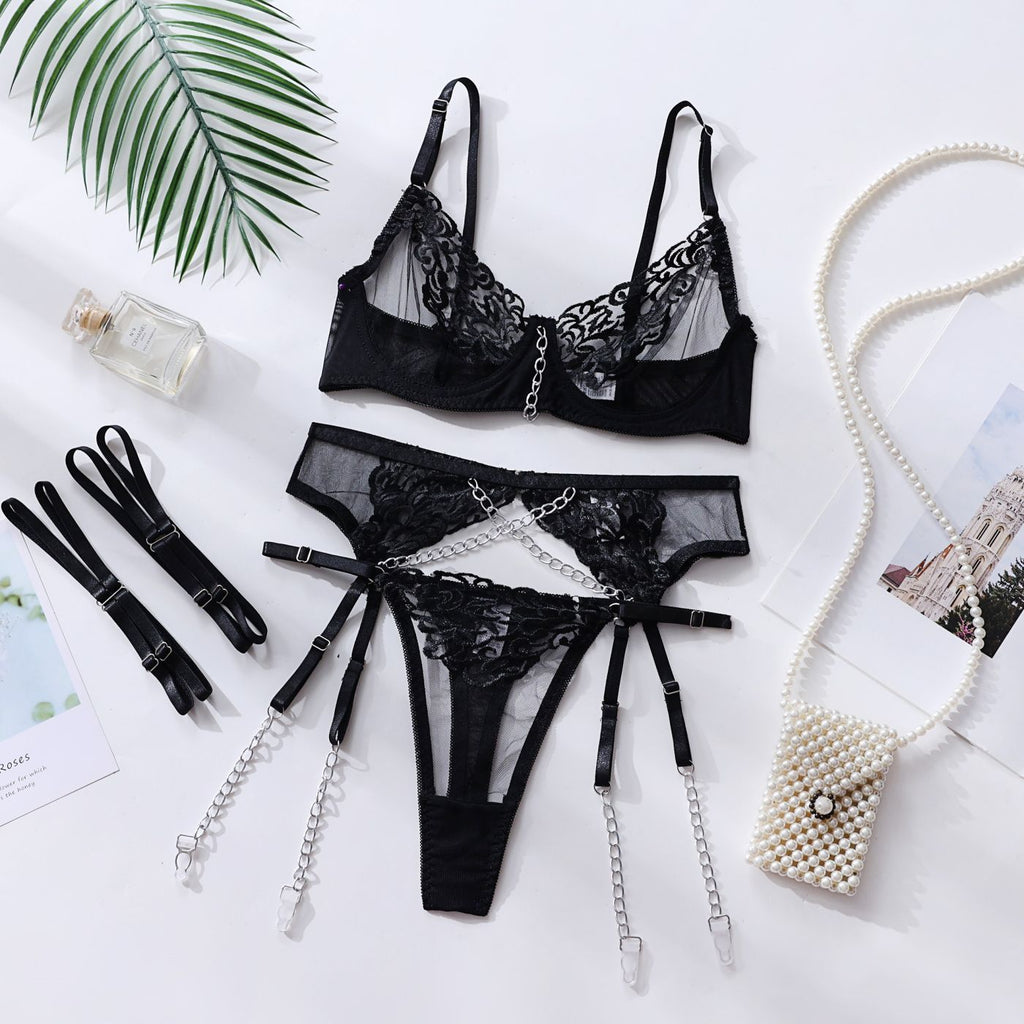 Conjunto Colette preto vista frontal: sutiã com aro, renda, correntes prateadas; calcinha, cinta-liga e ligas decorativas.