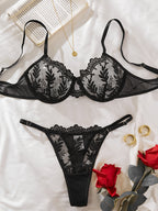 Conjunto Celeste preto, vista frontal. Sutiã push-up com aro, bordado em renda preta e mesh transparente, e tanga combinando.