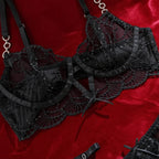 Detalhe frontal do sutiã preto Conjunto Orion. Aro, renda bordada vazada, laços e alças com elos cintilantes.